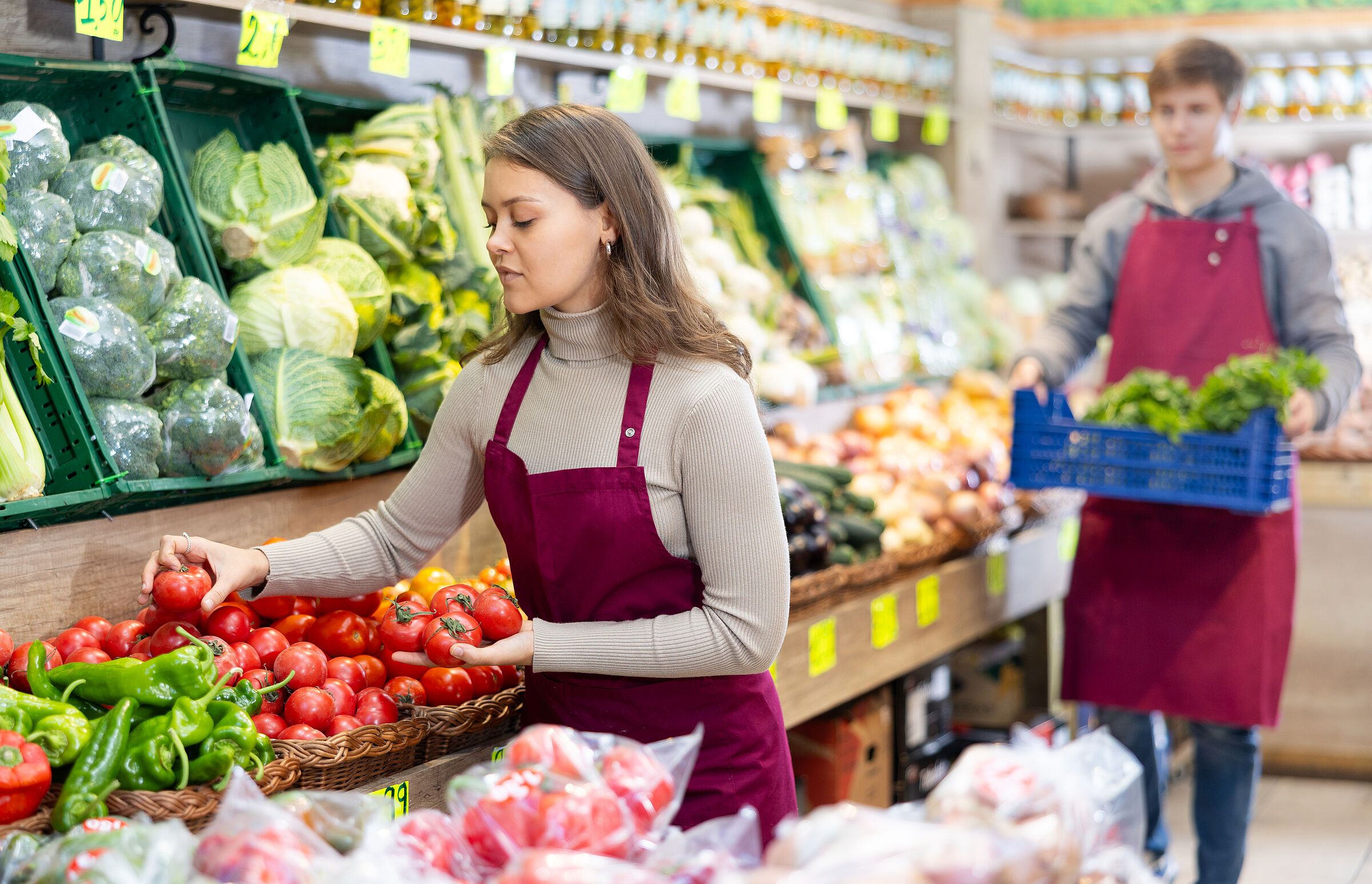 Wie geht es dem Personal beim Discounter und im Biosupermarkt? (Foto: JackF/adobe.stock.com) Eine Frau und ein Mann in Schürzen füllen die Gemüsetheke auf.
